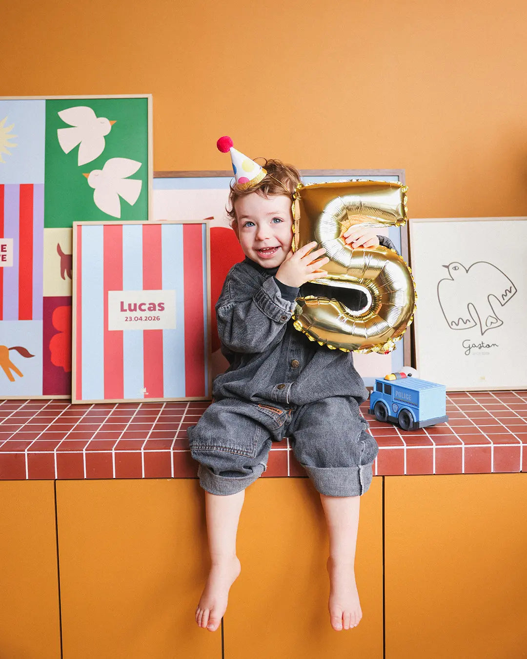 Enfant qui tient un ballon 5 ans devant la collection d'affiches ma petite vie